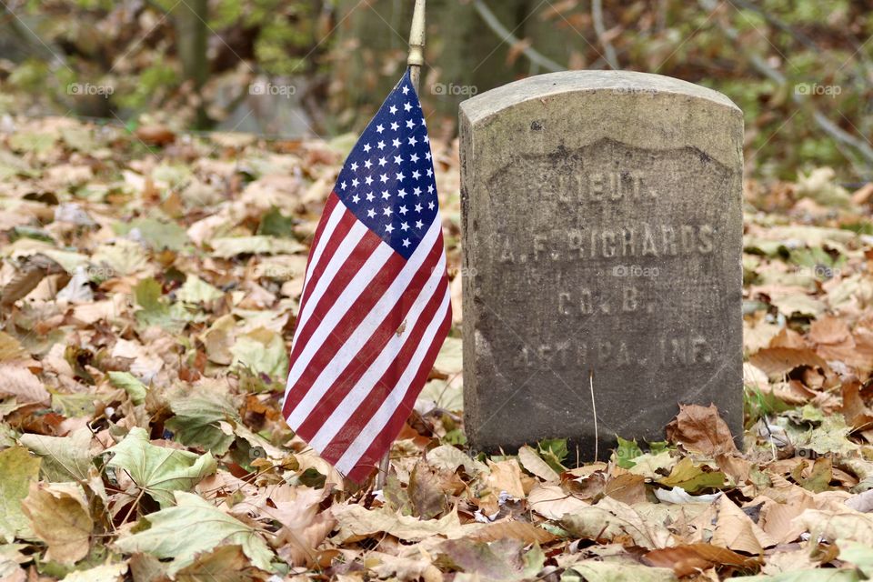 American flag beside an old tomb stone