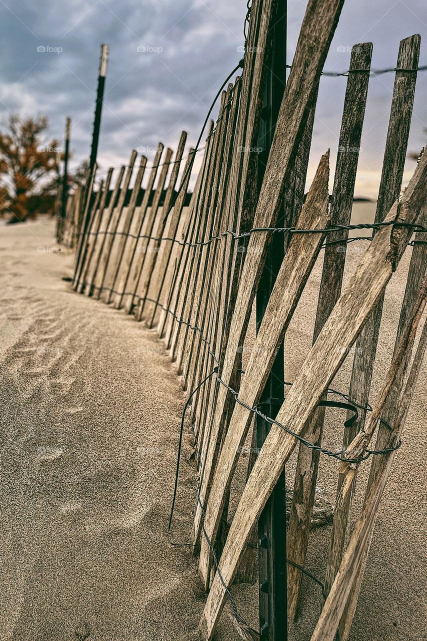 Beach fence line, fences on beaches, Michigan beach fence, footprints in the sand, lonely beaches, off season at the beach, empty beaches beach fence in decay, leading lines photography