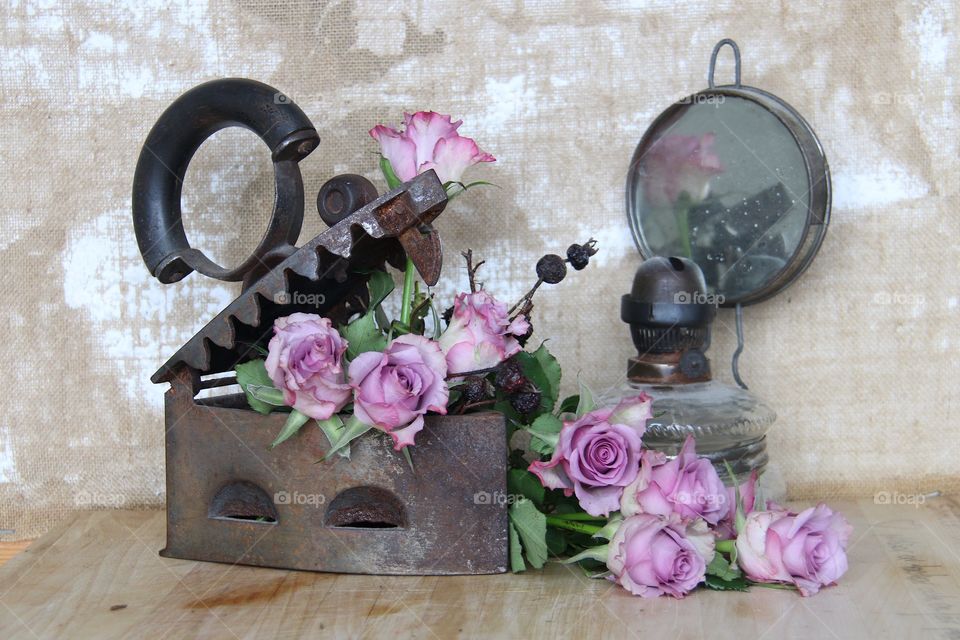 Pink roses in a iron and an old oil lamp