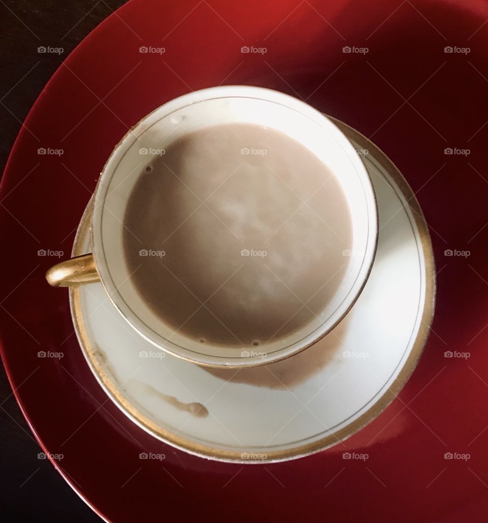 Cup of coffee on a white saucer and red background 