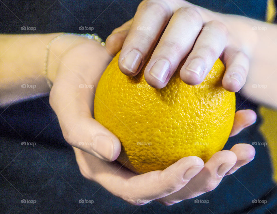 An orange in the hands of a girl