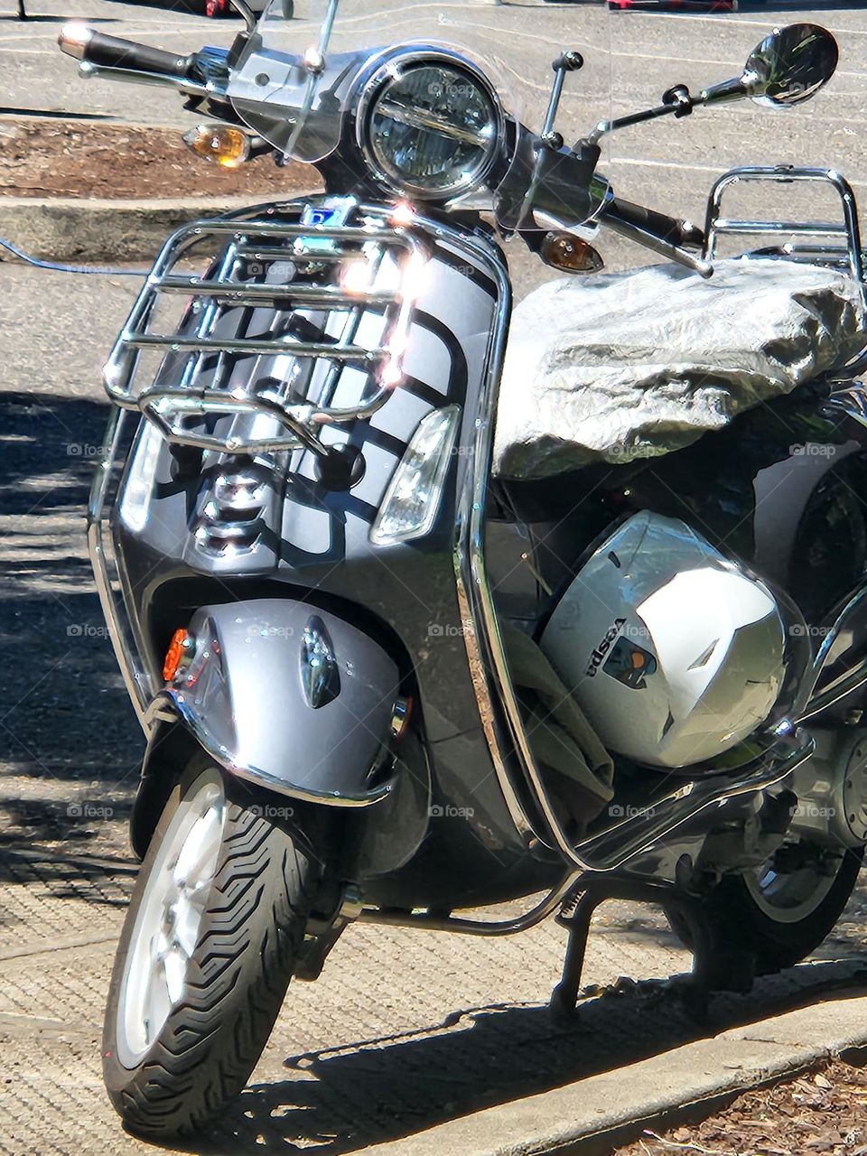 close up of shiny silver gray Vespa scooter with helmet