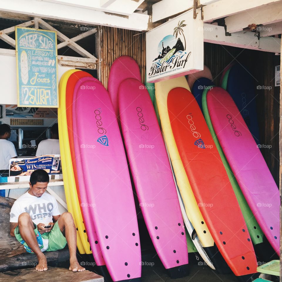 Surfboards for rent. A guy beside the colorful surfboards for rent. Surf's up! 