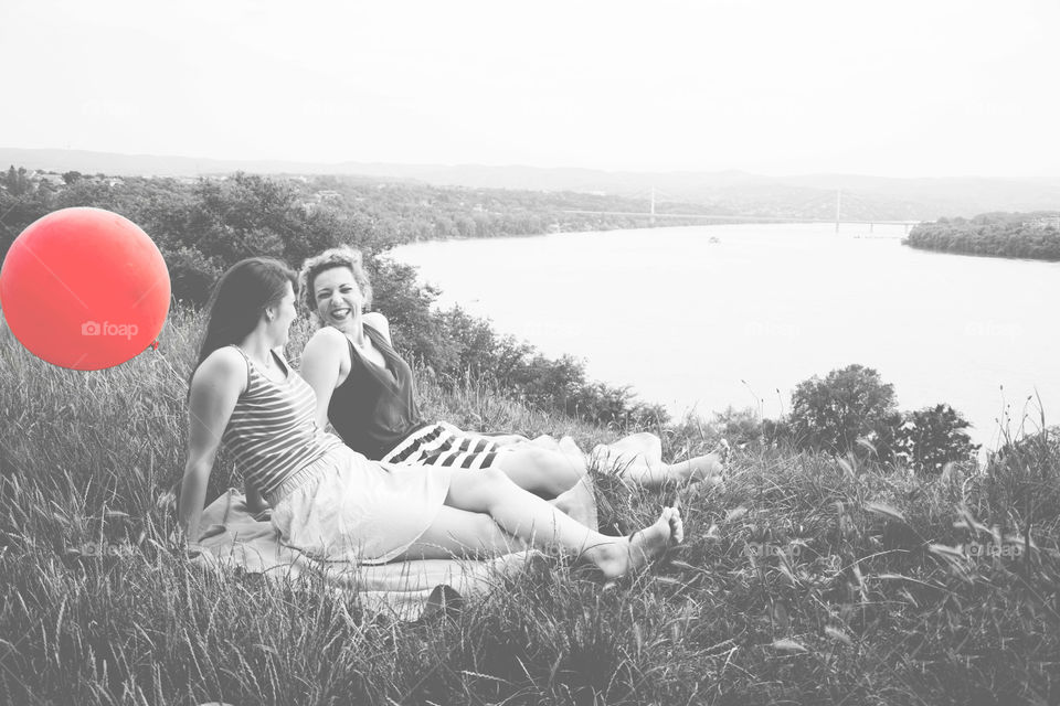 best friends relaxing. best girl friends laughing sitting up the hill