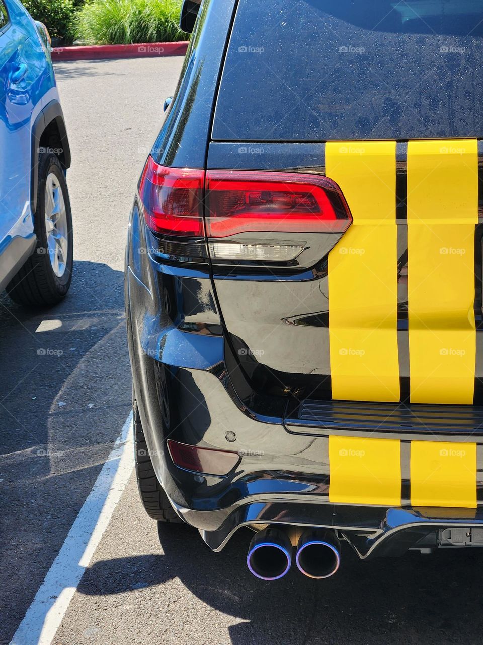 parked modern SUV with bold yellow racing stripes by the tail light