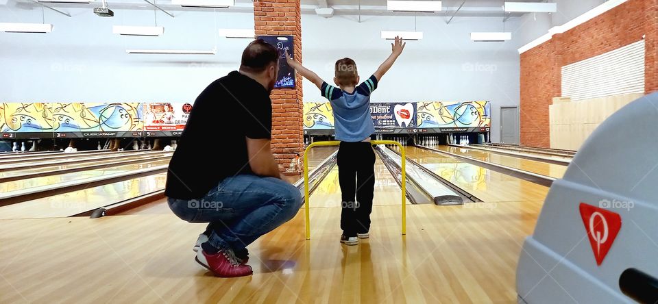 dad helps the kid play bowling