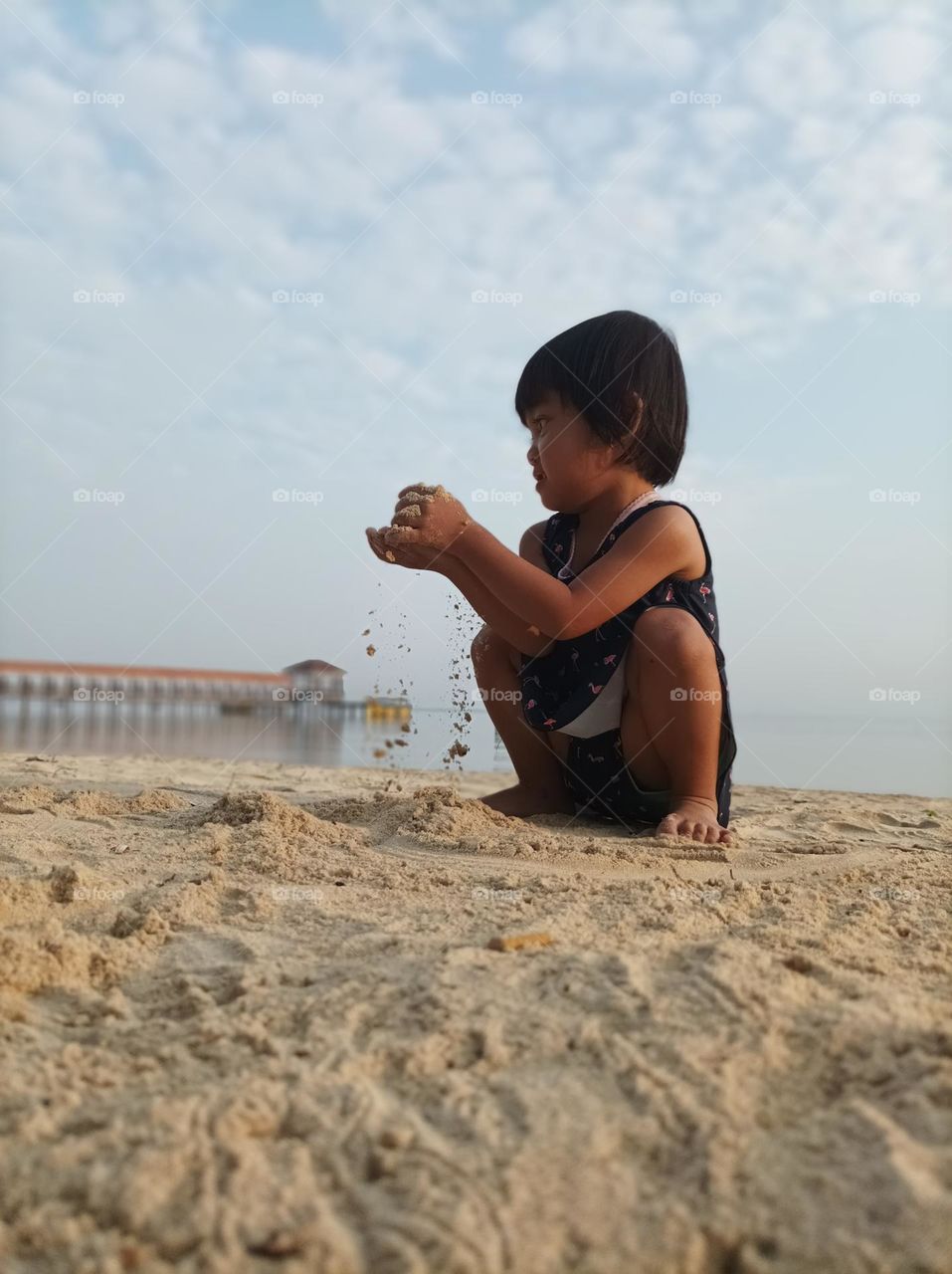 in the crispy morning, a beautiful little girl playing sand
