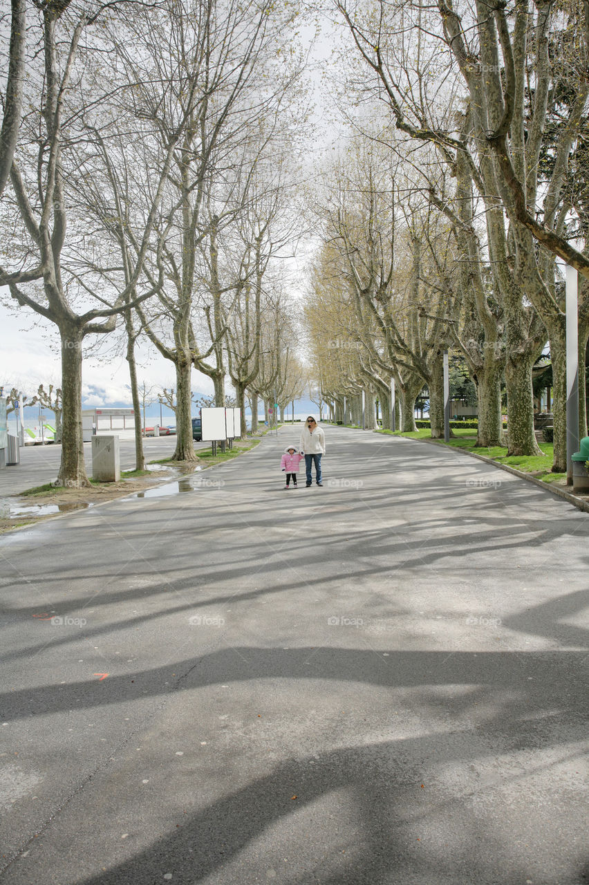 mother holds hand of little daughter walking in a beautiful road of