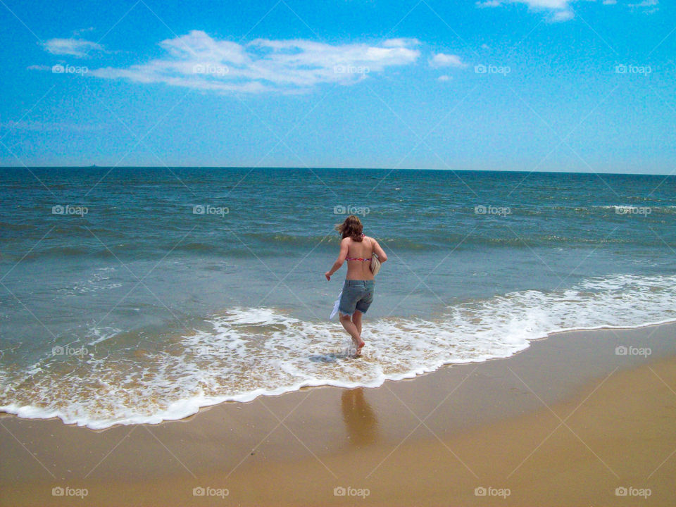 young woman running into the ocean