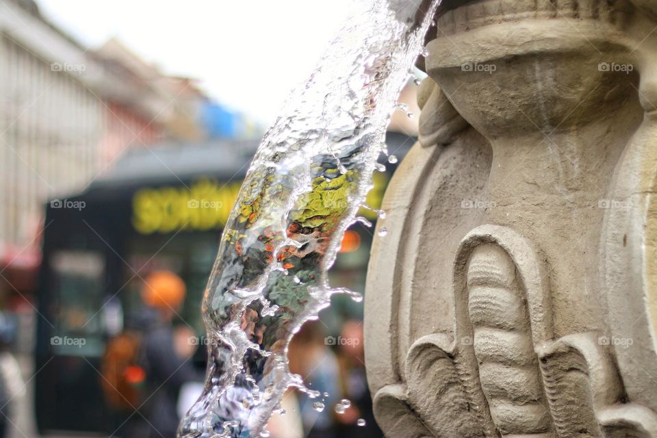 Close up of a stream of water spouting from a fountain in the city