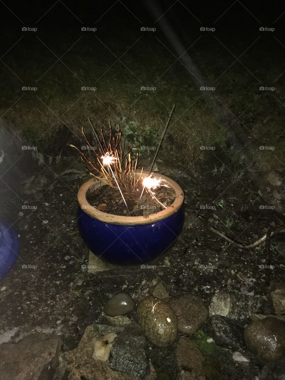 New Year’s Eve celebrations with burnig sticks. Stones, mud and grass surrounds the flower pot, where the burning sticks are located for celebrating a new year.