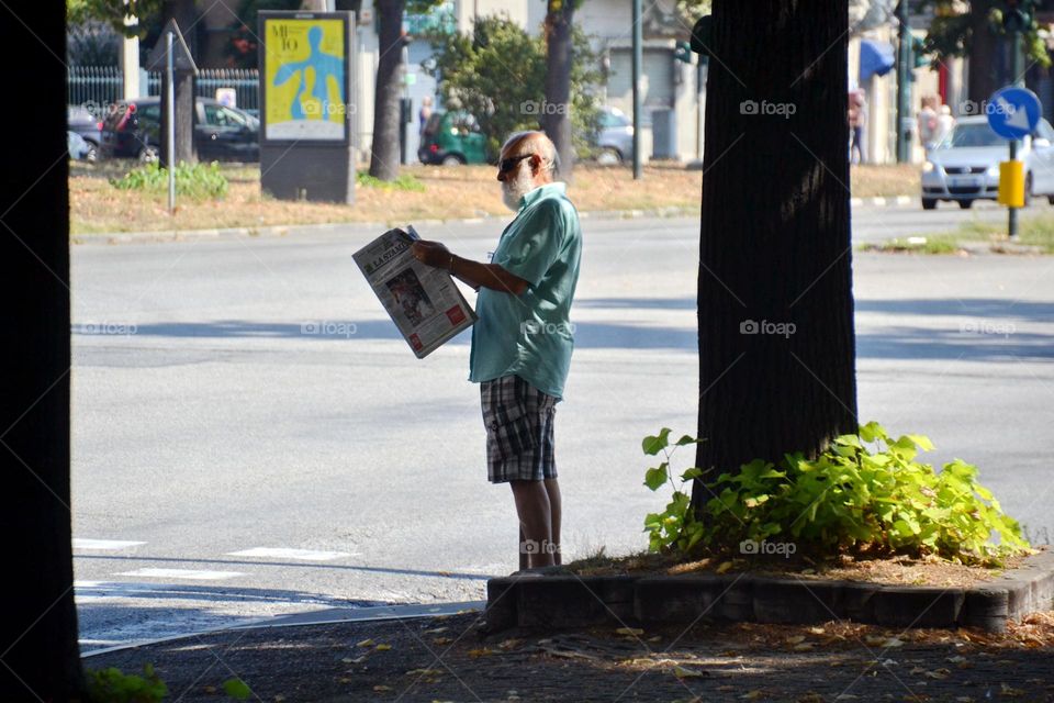 a man reads the newspaper walking on the street