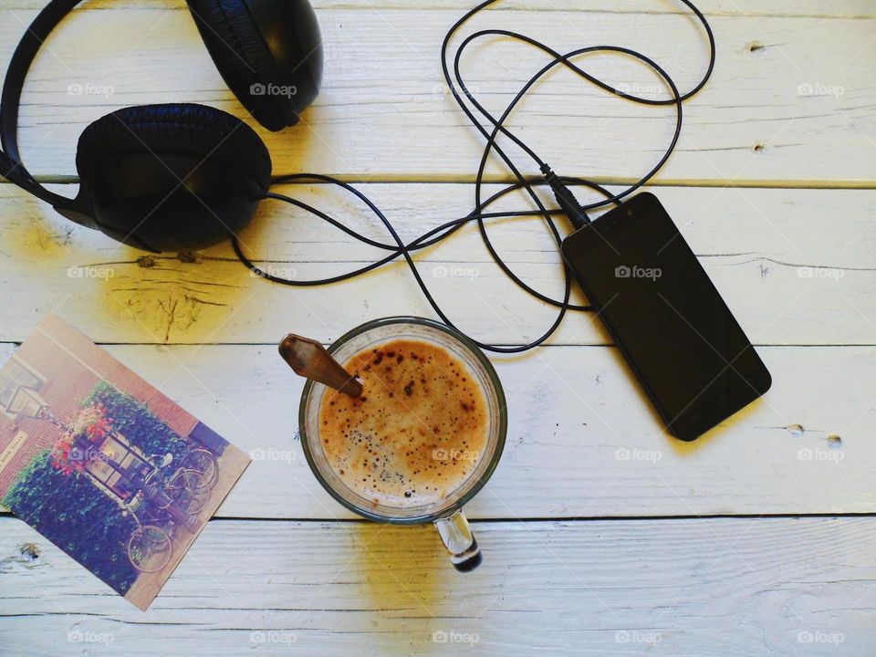 cup of coffee, smart phone, headphones on table