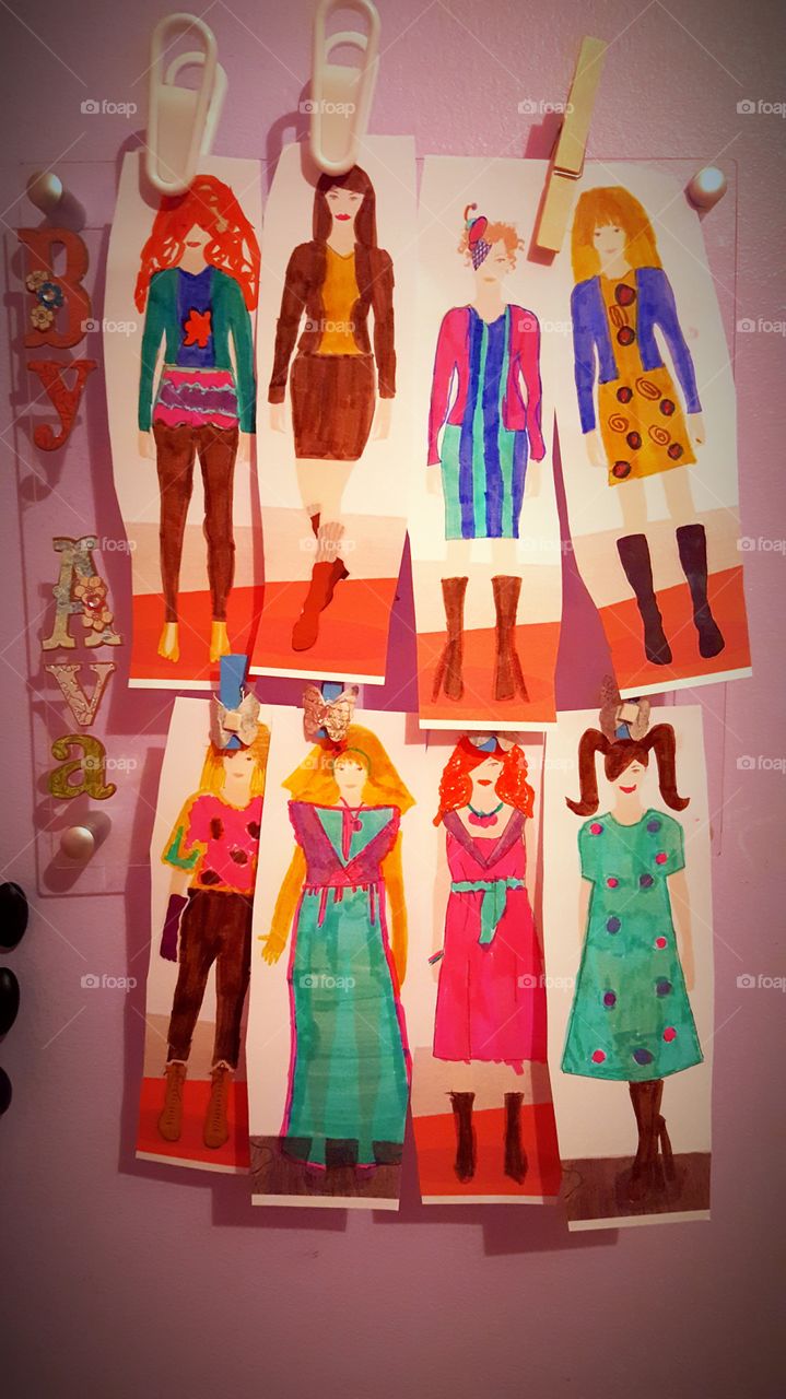 a little girl's fashion designs hanging on a wall for display