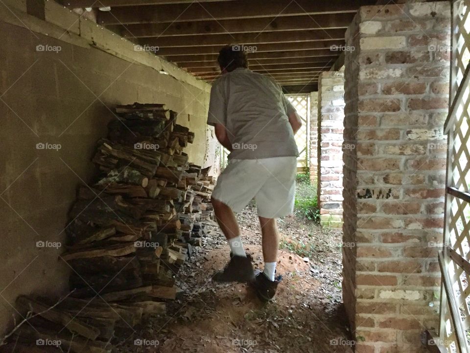 Man moving fire wood under a house