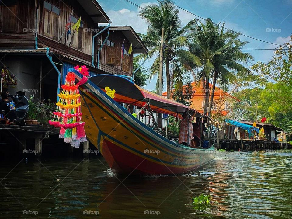A colorful boat rides down the canal at a popular floating market on the edge of Bangkok, Thailand.