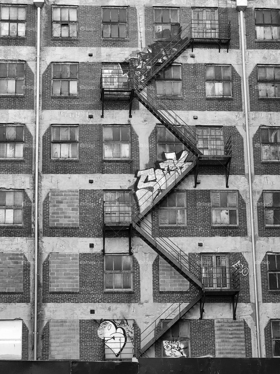 An external fire escape zigs and zags outside a dated brick building worn by time and graffiti