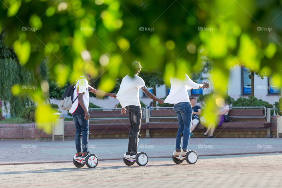 Friends riding gyro scooters in the park, fun times together