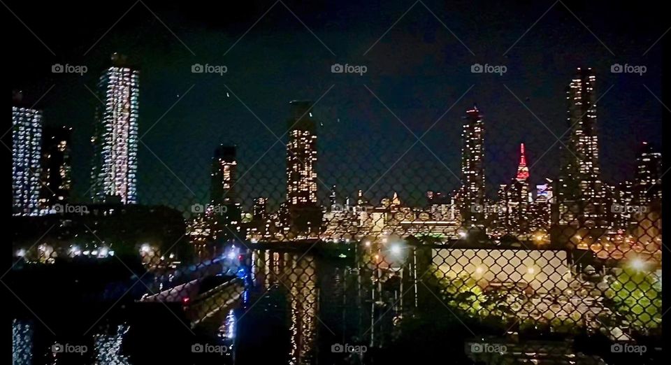 “Long Island City” and “Manhattan” can be seen from the pedestrian lane of the “Pulaski Bridge” at “Newtown Creek”. This is especially charming at night when all the high rises and skyscrapers are illuminated and sparkle. 2023. Hypnotic Productions