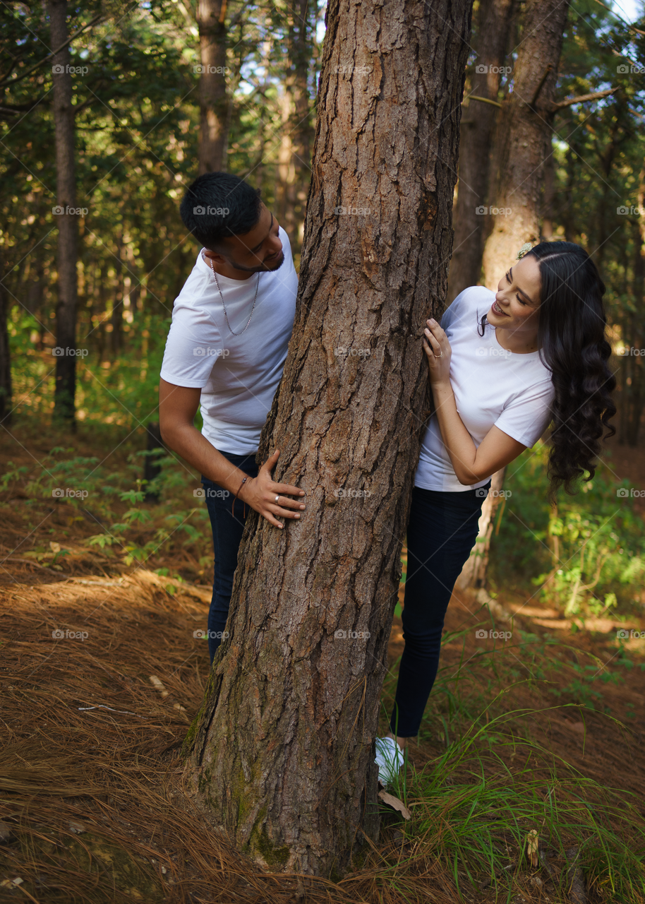 Couples of young people sitting in middle of the forest, enjoying a funny moment between them, in a sunny day.
