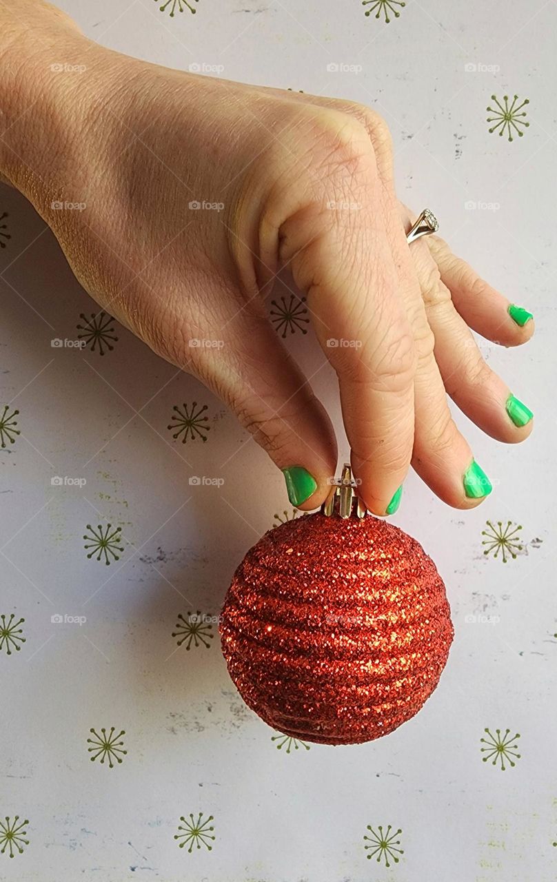 Christmas manicure: channeling the grinch holding an ornament.