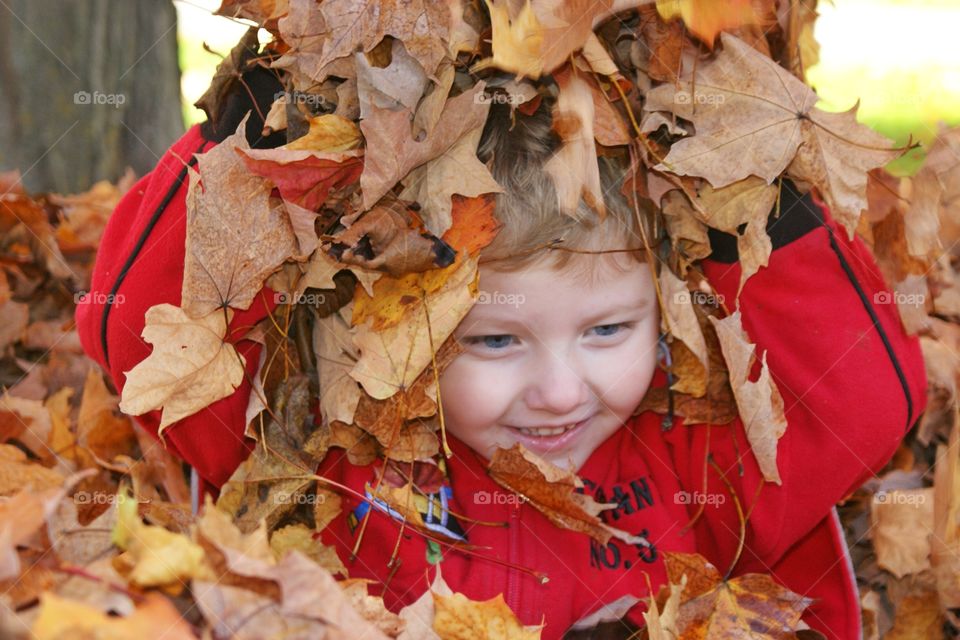 Close-up of a boy playing in autumn leaves