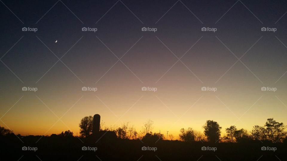 Sunset and moon over old farm town