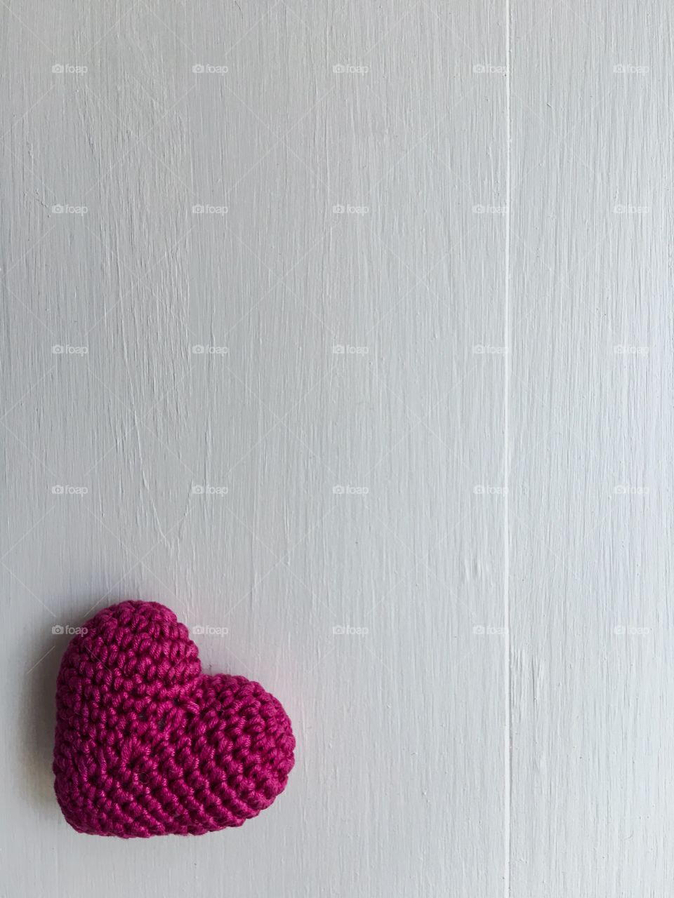 white wooden background with a knitted red heart in the corner