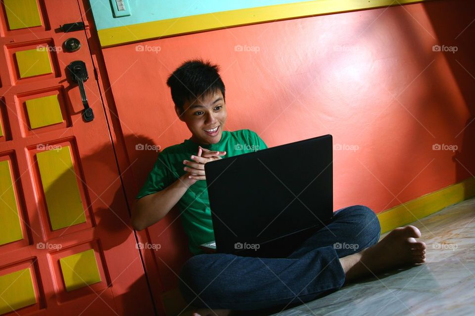 young asian teen with a laptop computer in a living room