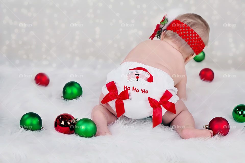 Back view of newborn baby with red and green Christmas balls
Rear view of little baby with ho ho ho diaper playing with Christmas balls.