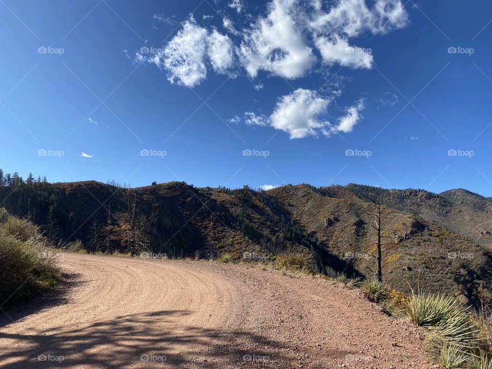 Dusty, dirt road winding through a mountainside. 