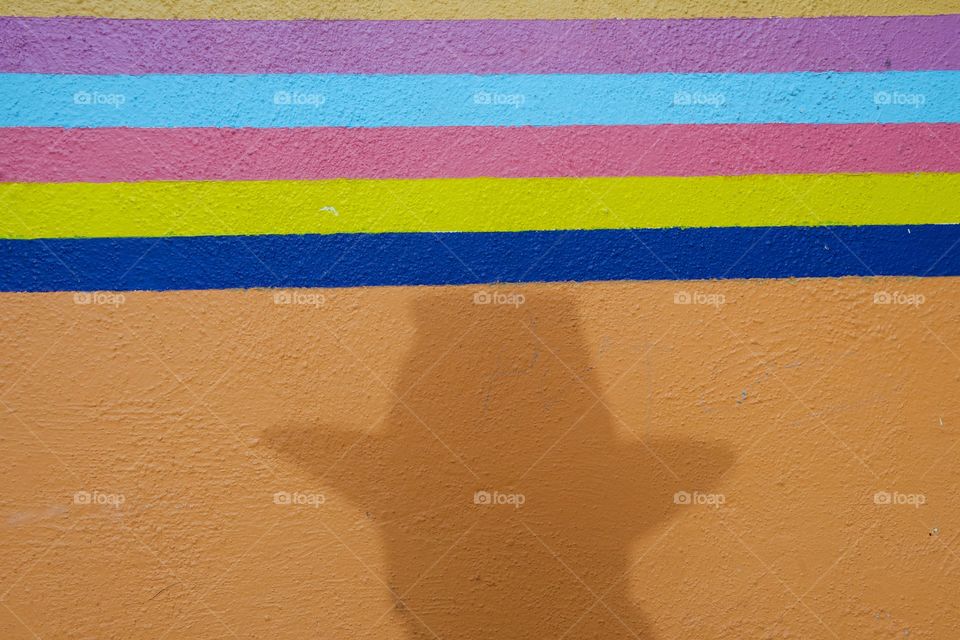 Shadow of a man’s face on a colorful outside wall .