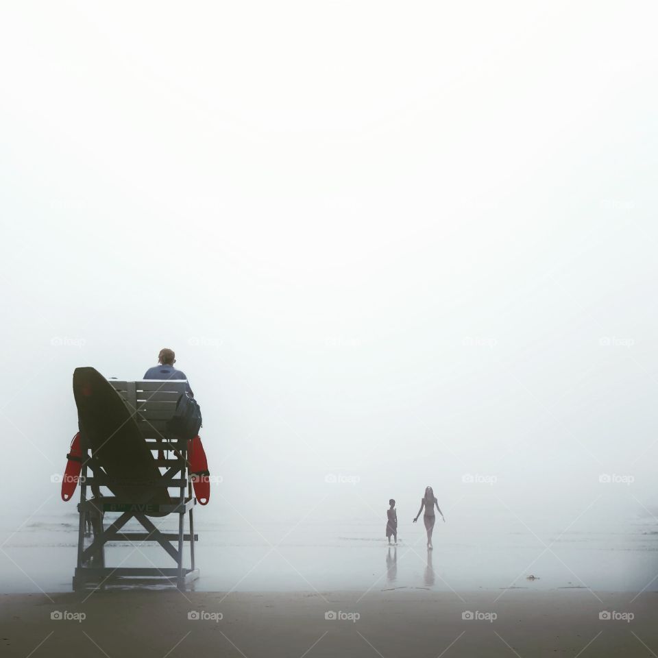 People on beach during foggy day
