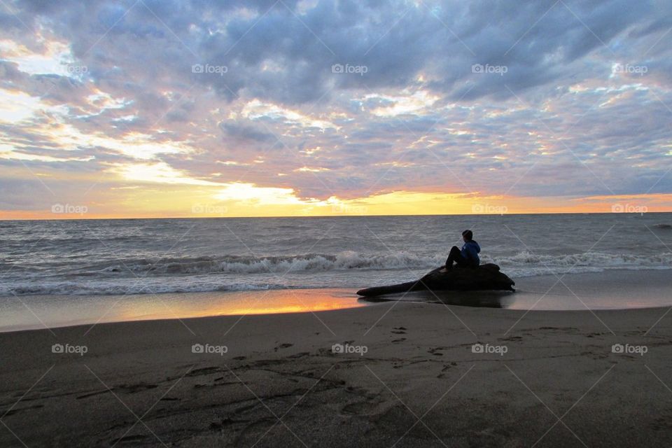 Boy Sitting on a Log in Sunset