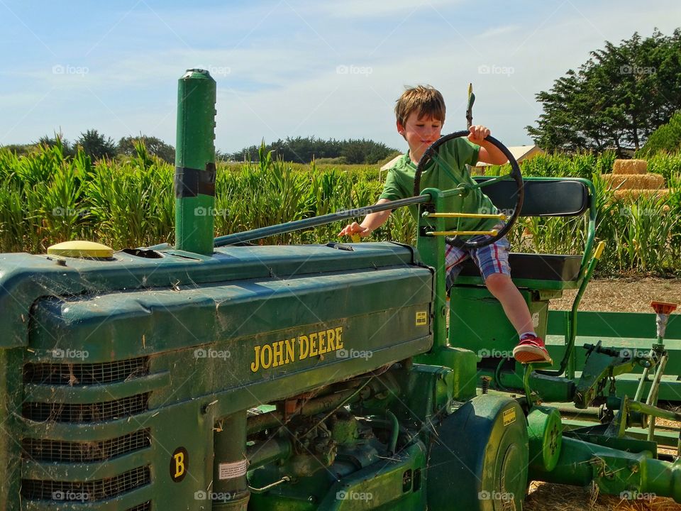 Boy On A Tractor. American Farm Boy Playing On A John Deere Tractor
