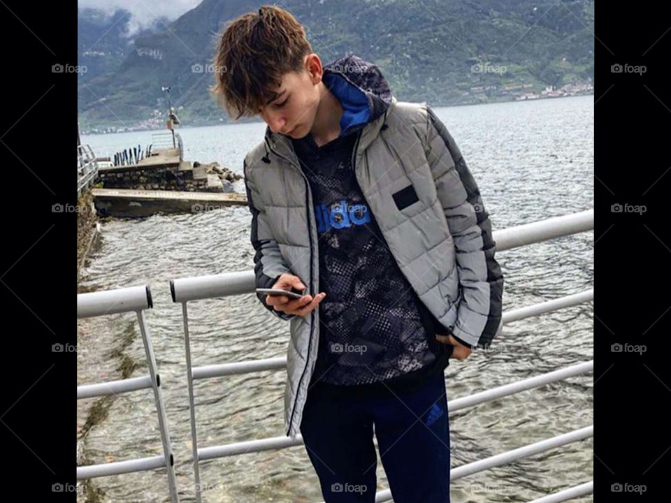 This is me in Atalanta, Italy, by a river with green mountains in the foggy background.