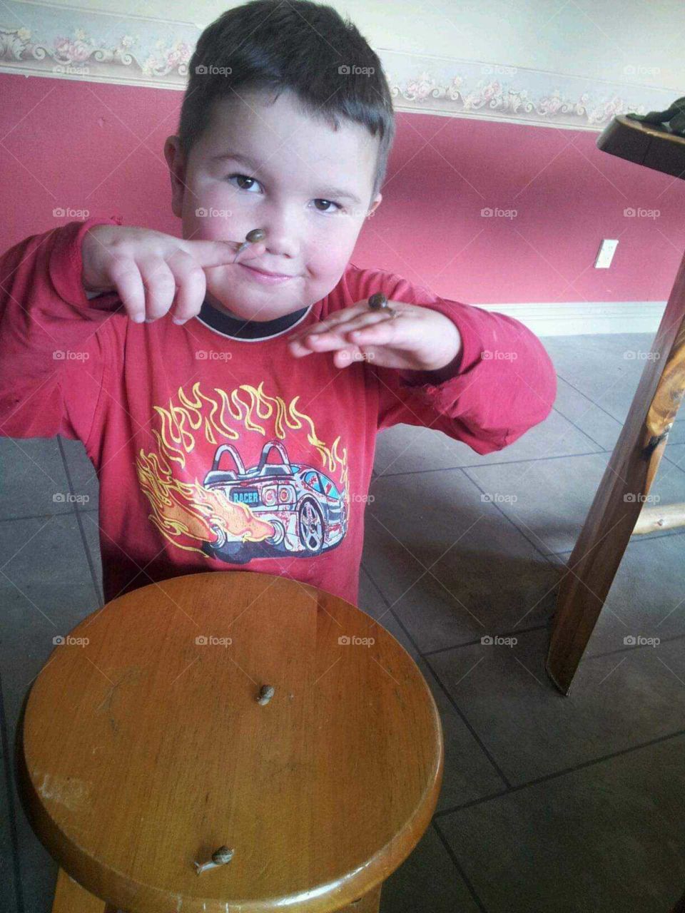 A little boy finds littles snails from in the garden. He is intrigued with his new friends.