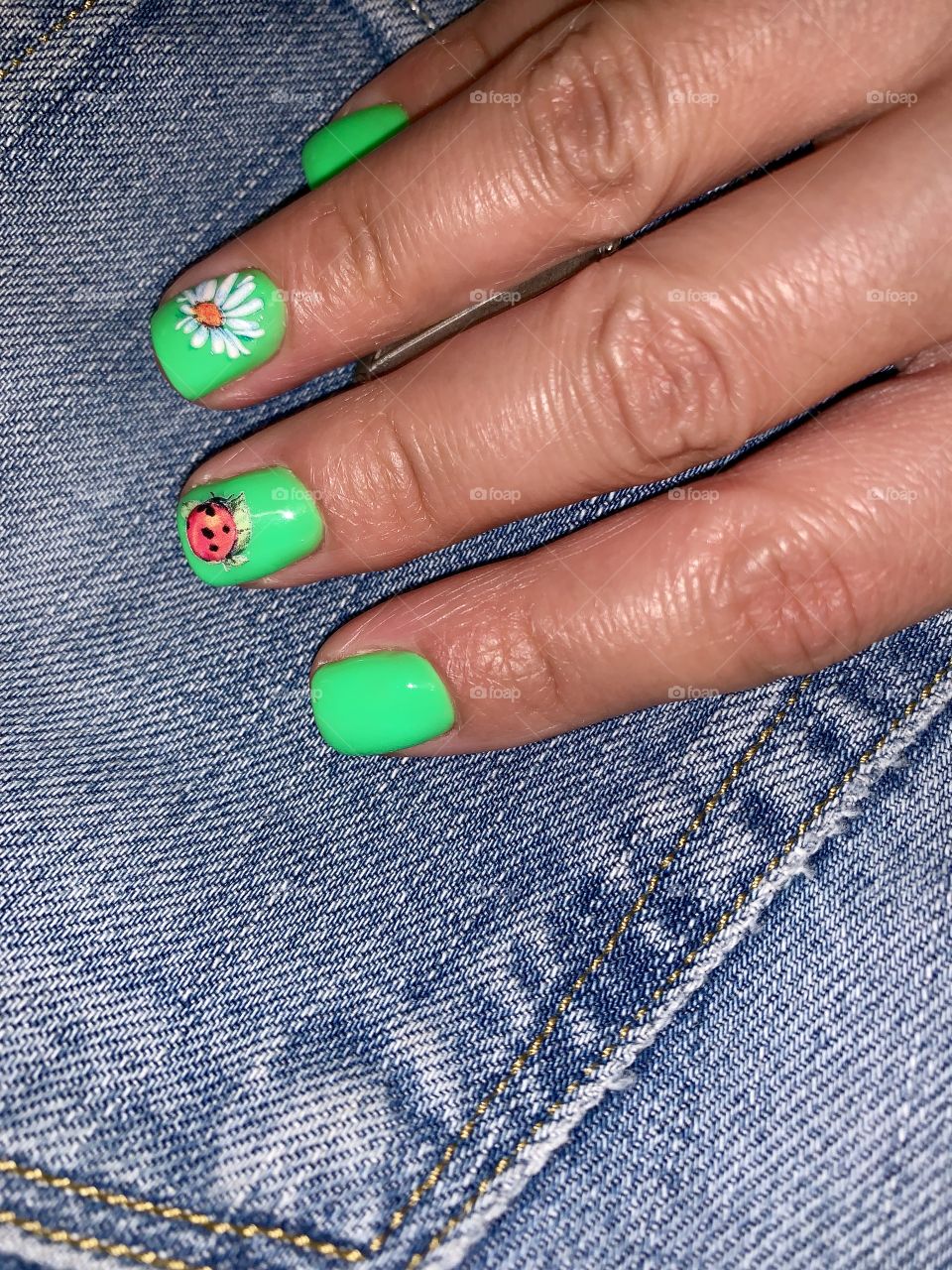 hand with bright green manicure on a denim background