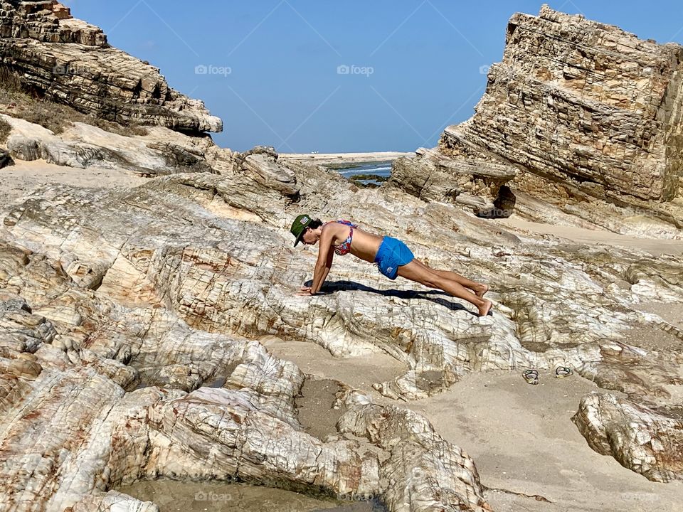 Plank on the rocks in the desert beach. Social distance 