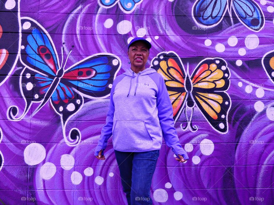 Color Purple - standing in front of the purple mural with her arms outstretched to become one with the art