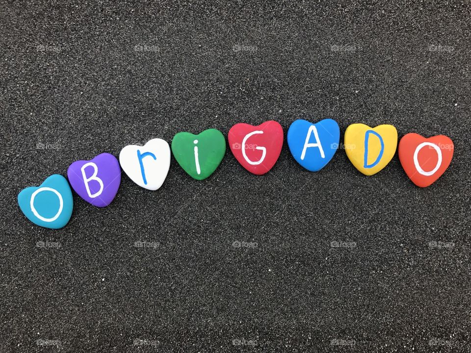 Obrigado word with colored heart stones over black volcanic sand