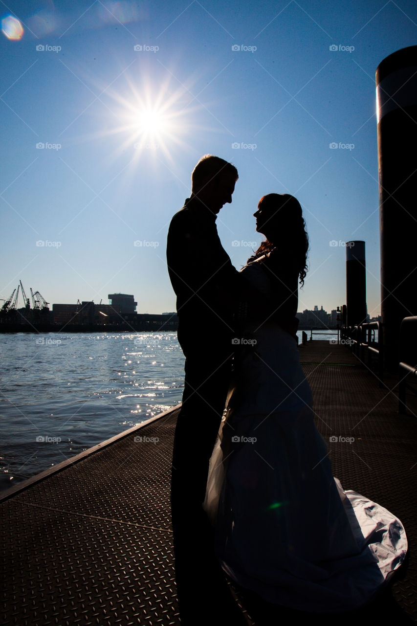 Silhouette of a couple under the sun on the riverside