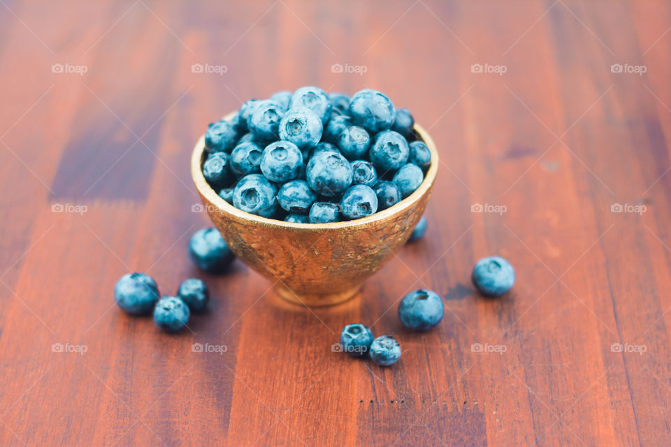 Fresh Blueberries in a Gold Bowl on a Wood Table