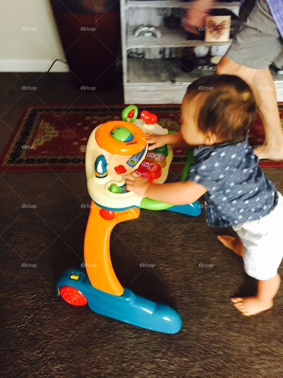 Baby boy walking with his walker in the livingroom