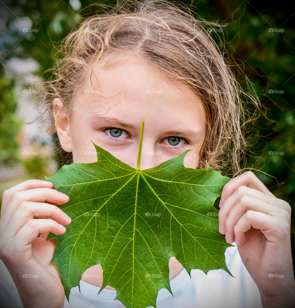 Girl with eyes as green as the maple leaf and forest around her