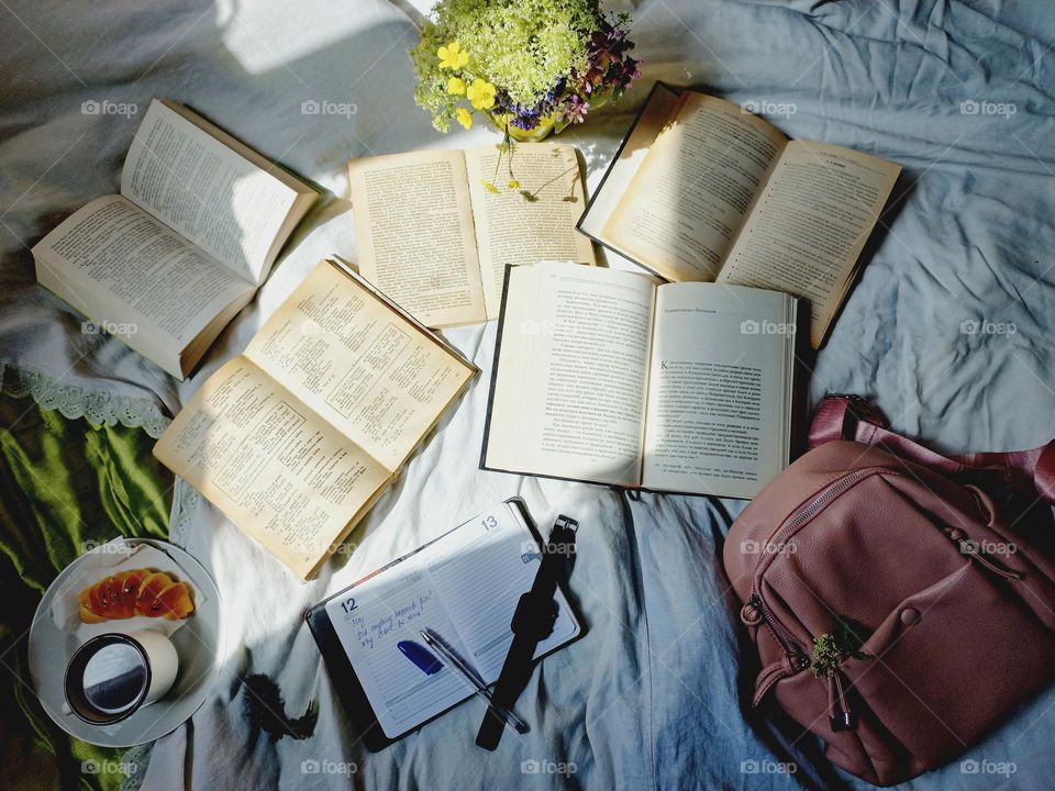 spread out books in bed and coffee and a bun.