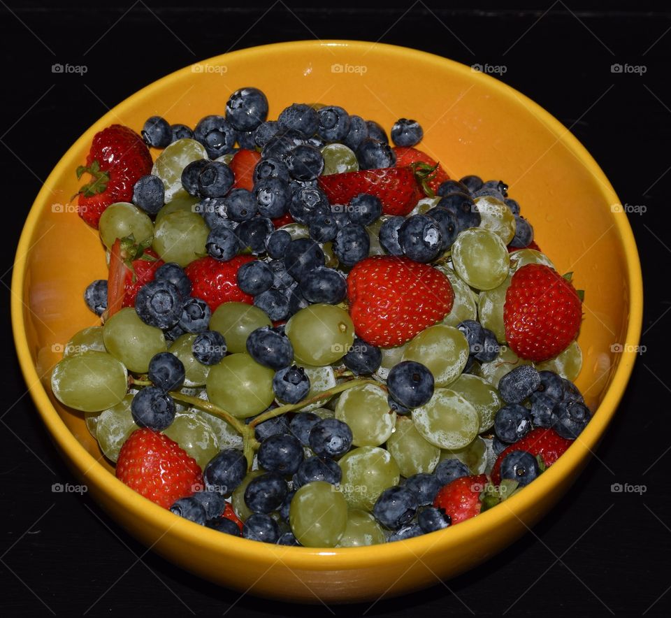 Let's share a huge bowl of fruit,  strawberries,  blueberries and grapes