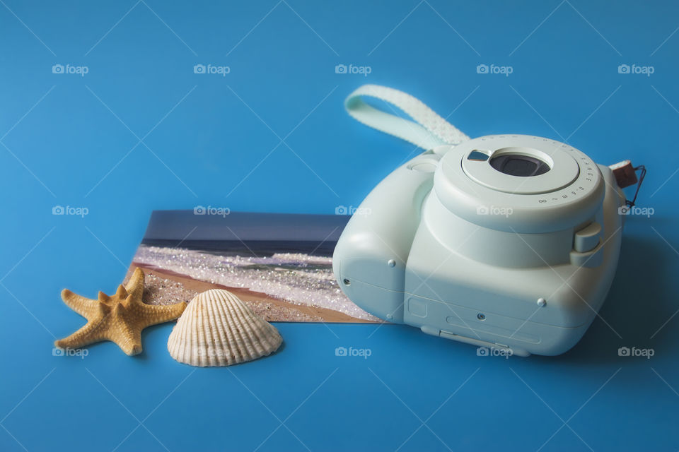 Postcard of sea, seashell and camera on blue background. Conceptual photo of summer time