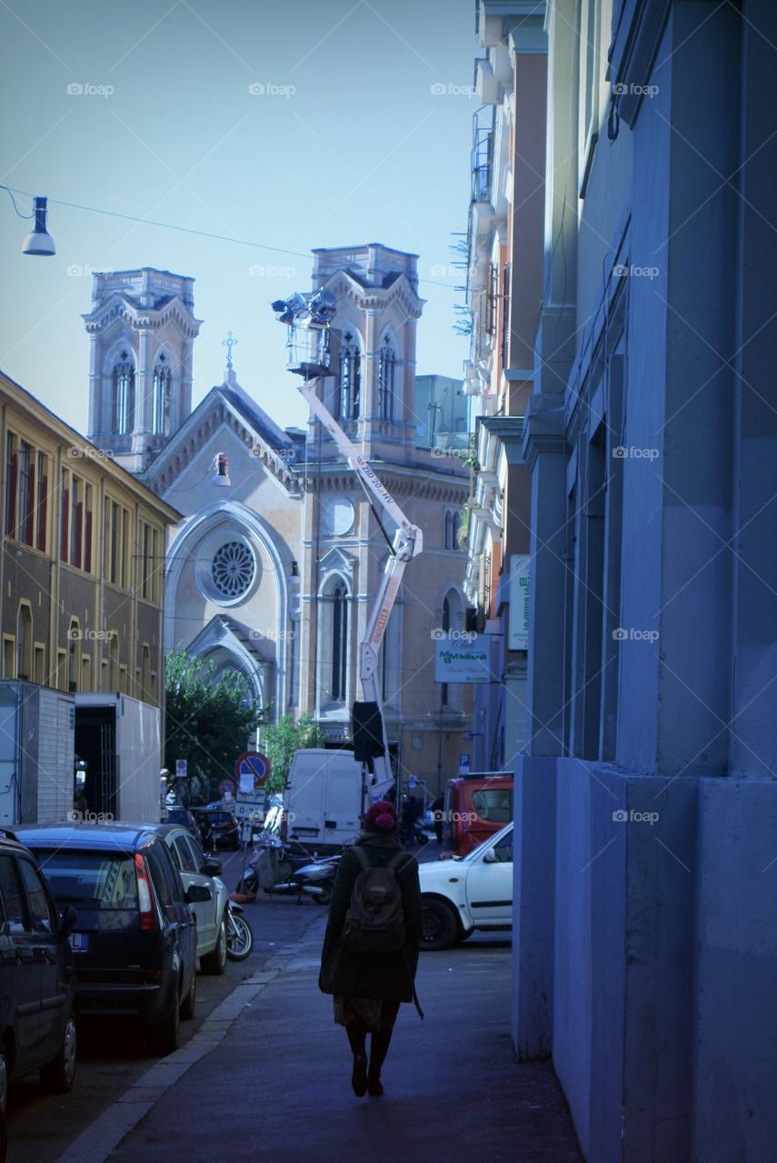A woman walking in Rome, between little streets and ancient buildings.