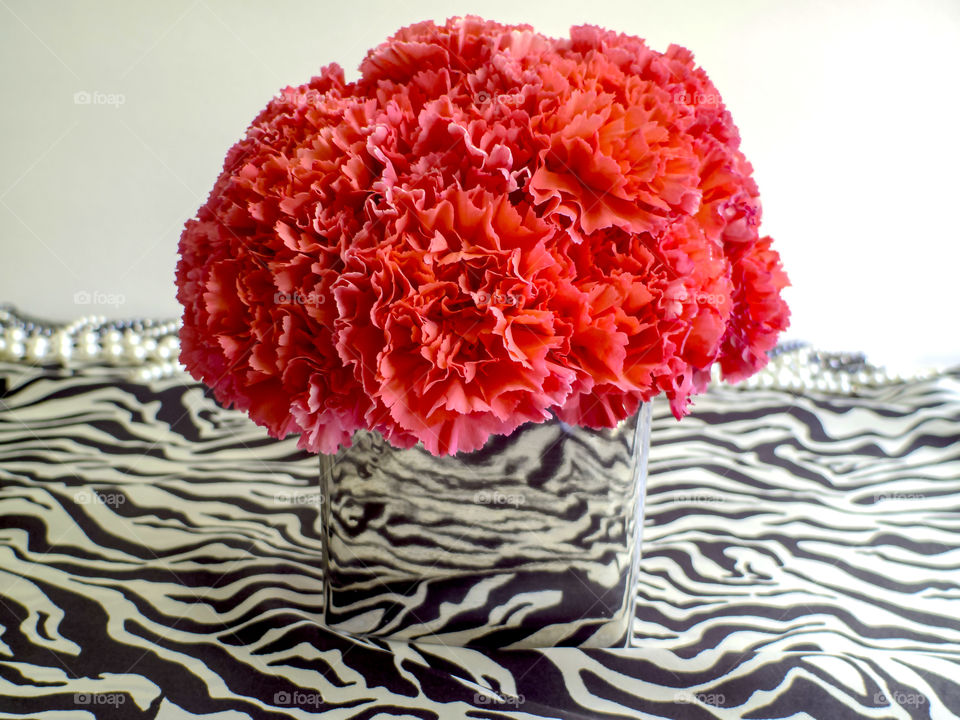 Pink carnations bouquet in a silver vase on animal print